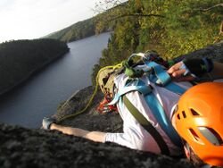 climber lying on a cliff next to a river